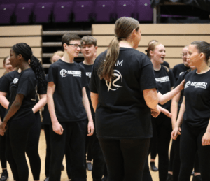 Staff member talking to students instructing them on the choreography they are learning